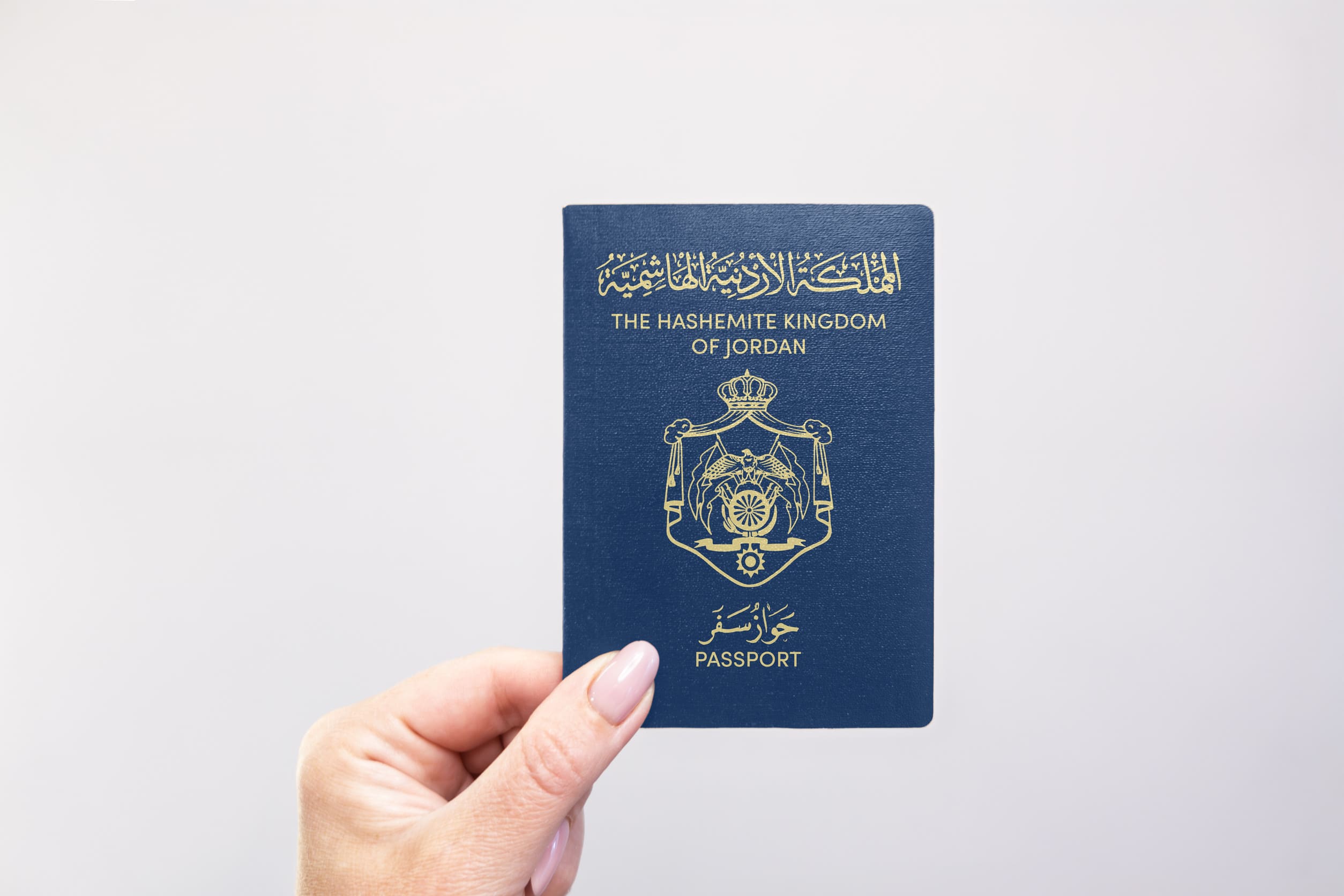 Close Up Of A Jordan Held Passport In Hand Against A Plain