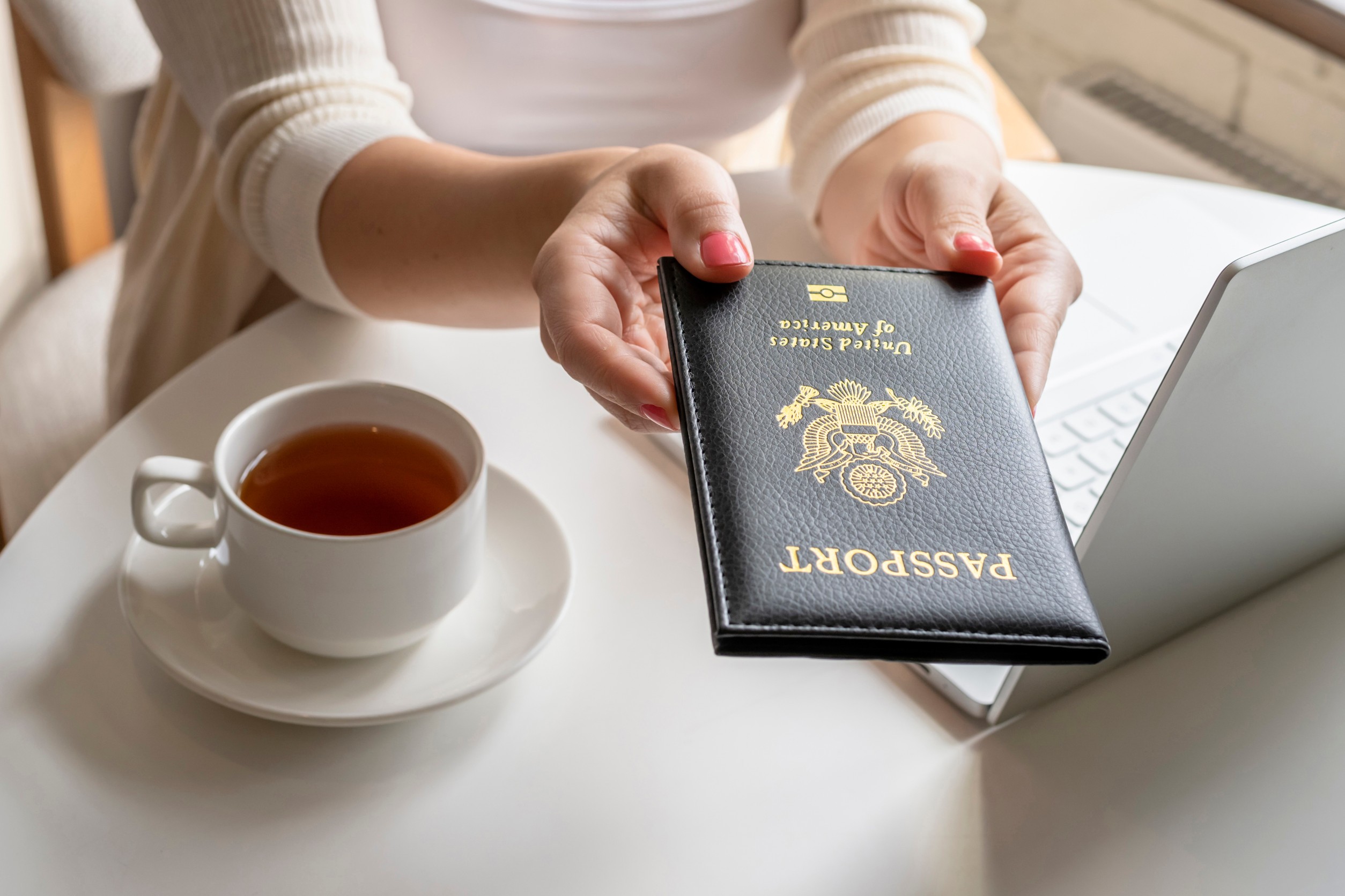 Woman Tourist Having Breakfast With Cup Of Coffee Holds Out American Passport